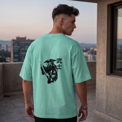 Person wearing a light green t-shirt with a graphic design, standing on a rooftop with a cityscape view.